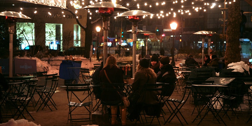 People sitting outdoors under string lights in winter clothing, displaying Dunedin nightlife.