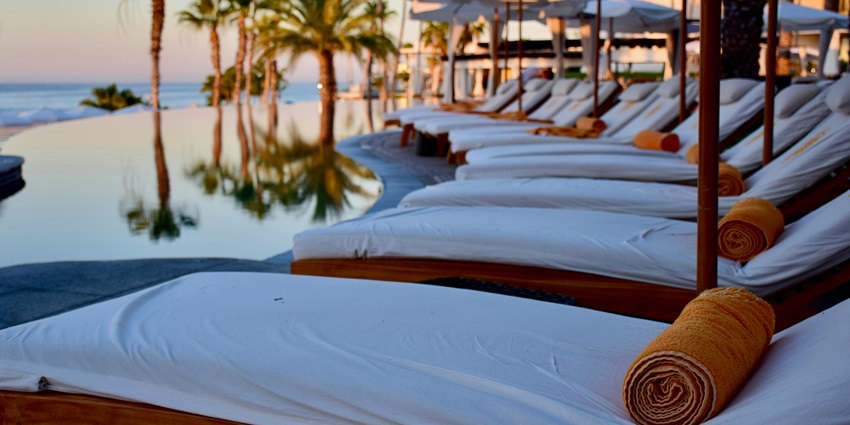 Elegant white lounge chairs arranged around a pool, set against a tropical backdrop