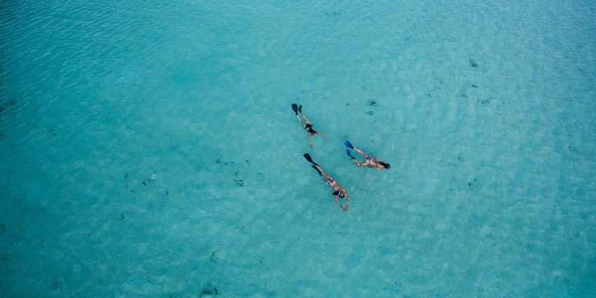 An aerial view of people snorkelling in the turquoise waters, one of the best things to do in Maldives in October