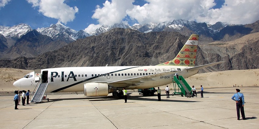 An aircraft getting ready to begin its first journey of the day on a runway set amidst snowy mountains.