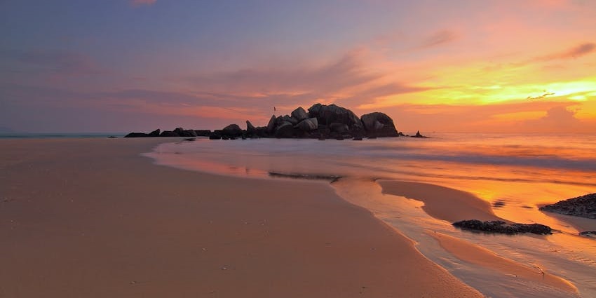 View of vibrant sunset hues at Jalloonda Beach, with the waves crashing the shores