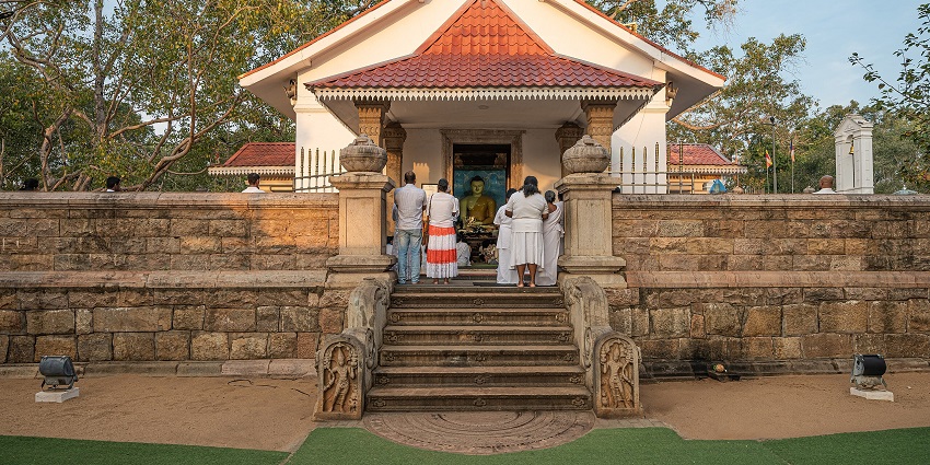 Devotees in white garments worship at a shrine near the Jaya Sri Maha Bodhi tree.