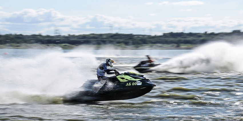 An image of jet skis, speeding across water, creating large sprays behind them.