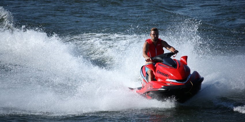 People jet skiing powerful ocean waves with a city skyline misty background, one of the best water sports in Australia.