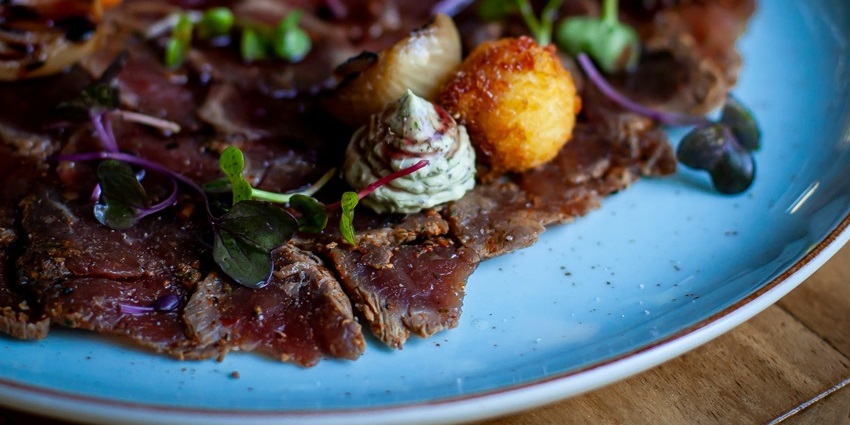 Image of a plate of beef jerky served with mints, onions, and small meat balls on top and side