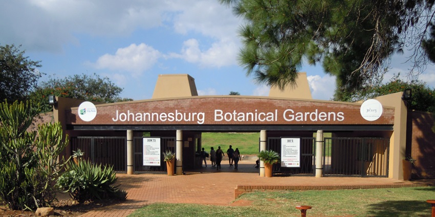 The entrance of Johannesburg Botanical Gardens with a sitting area in the foreground.