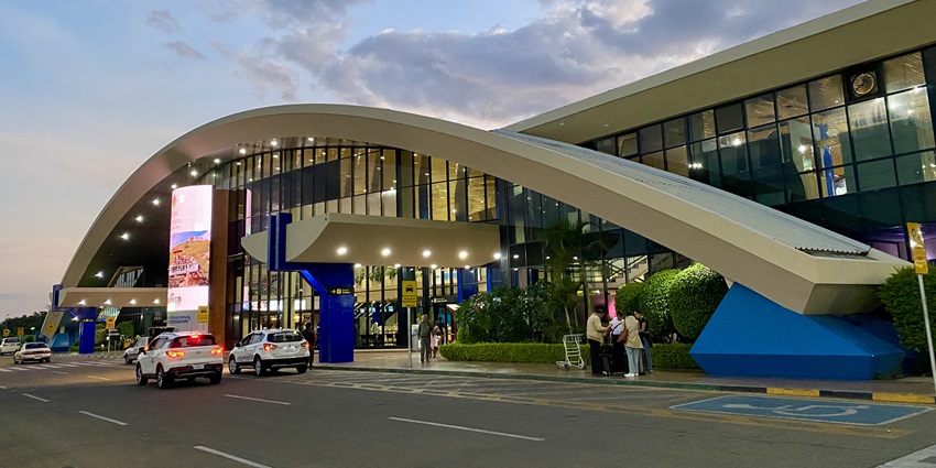 Passengers are standing outside Jorge Wilstermann International Airport during the evening.