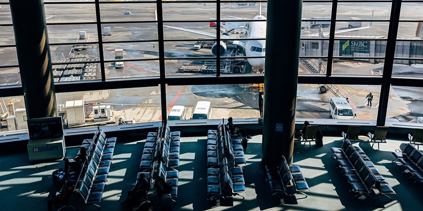Sunny day inside an airport with empty chairs facing both directions and arranged in rows