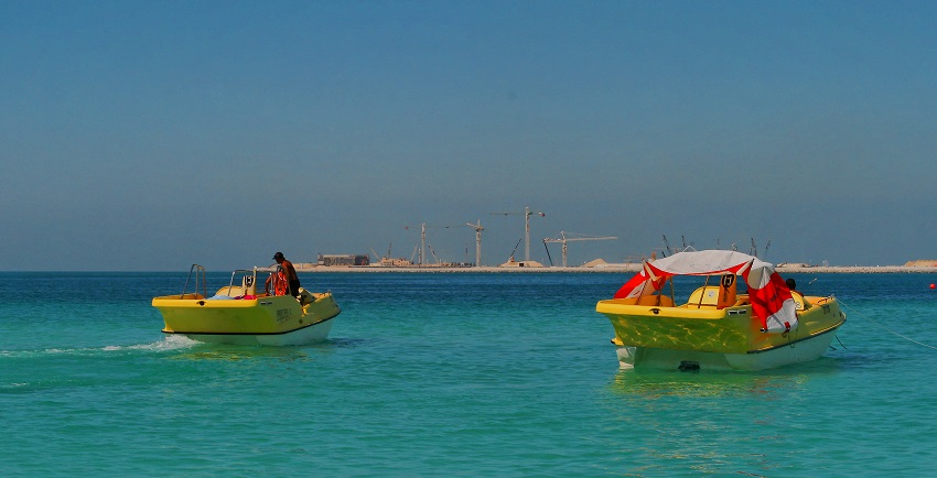 Two boats float on turquoise waters in Dubai, preparing for exciting parasailing trips.