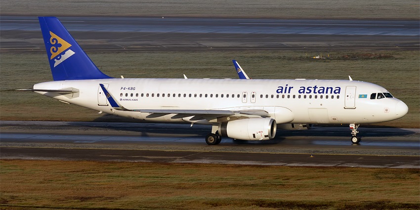 Blue and white commercial aeroplane parked on the runway of an airport and green plains
