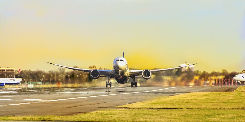 An open runway with green fields on both sides and a plane preparing to take off