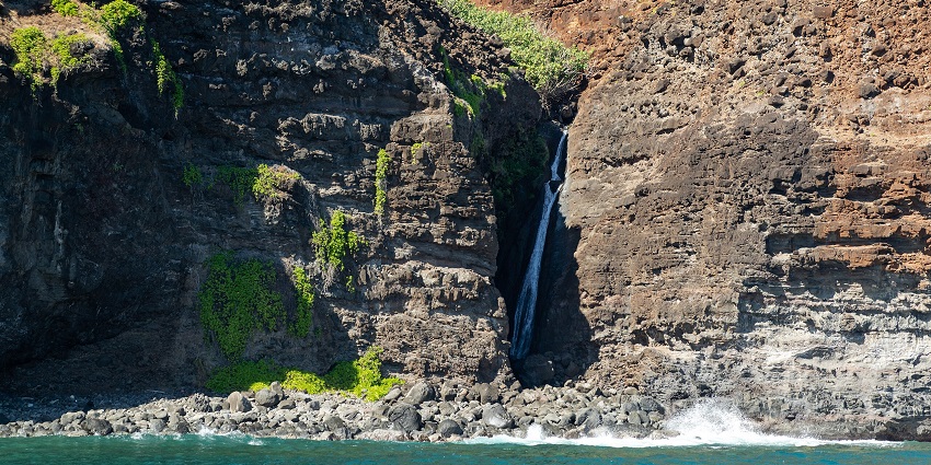 A waterfall along the Na Pali Kalalau Trail, a well-known hiking route in Kauai, Hawaii.