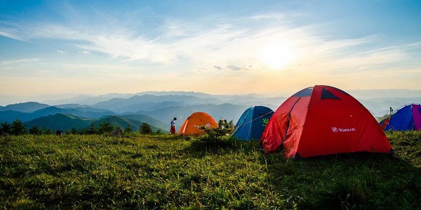 View of tents on verdant landscapes near Pawna lake, with bright sunny sky