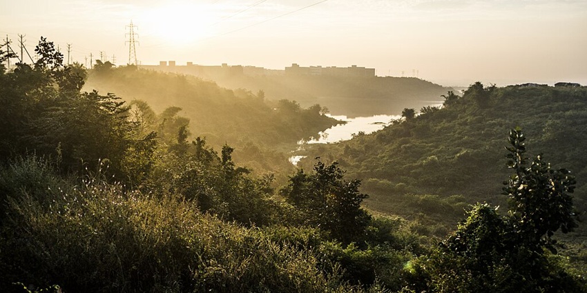 Kaliasot Dam reservoir with a distant water body surrounded by dense greenery and sunset