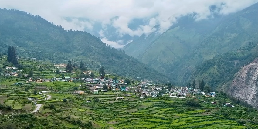 A serene view of the Kalpeshwar in Uttarakhand, surrounded by dense greenery and mountains