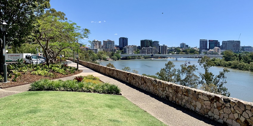A stunning riverside view of Kangaroo Point Cliffs, with climbers scaling the rugged rock face.