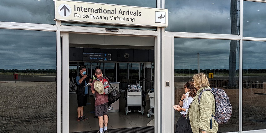 Passengers arrive at the airport, walking through the entrance of Kasane Airport.