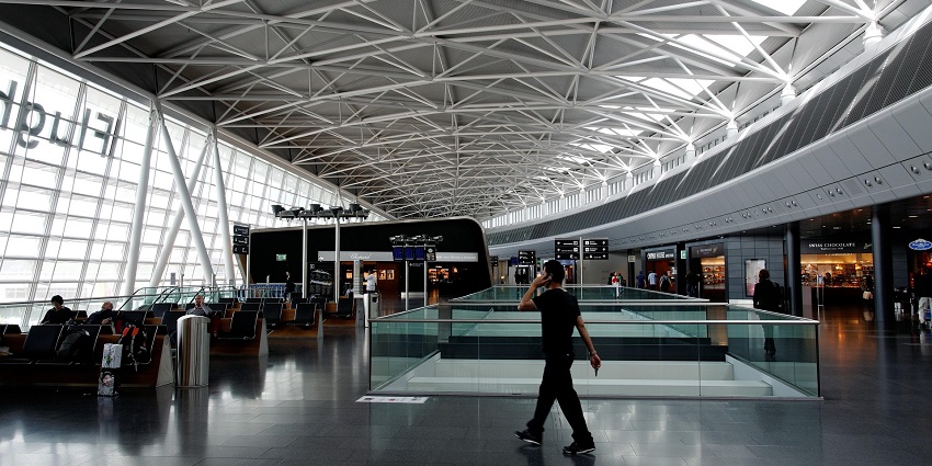 A departure hall of an airport with a man walking while holding a phone to his ear.