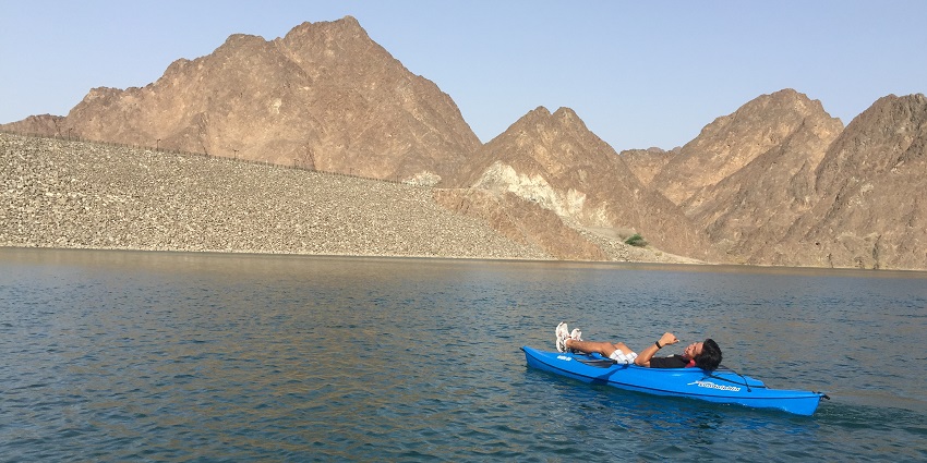 A person enjoying kayaking on Hatta Dam’s tranquil waters, surrounded by rocky landscapes