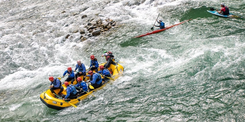 Kayakers paddling through the flowing waters of a scenic river, surrounded by rocky cliffs.
