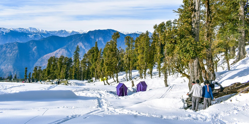 A trekker standing on the snow-covered peak of Kedarkantha, a must-visit place.
