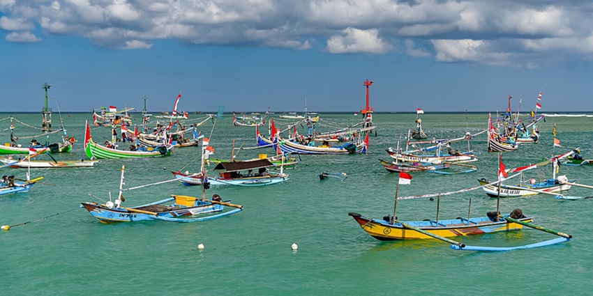 Boats floating on the calm waters of Kedonganan Beach under a clear sky.