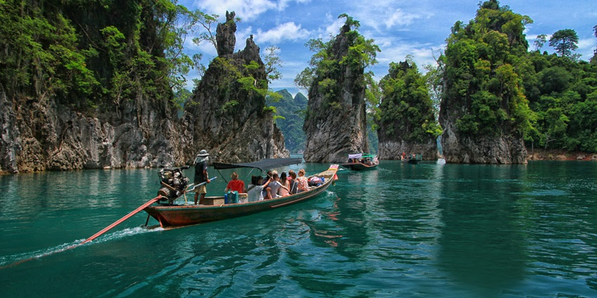 A rainforest park with limestone cliffs, caves, and floating bungalows on emerald lakes.
