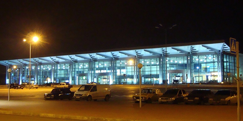 Kharkiv International Airport terminal at night with parked cars and illuminated architecture