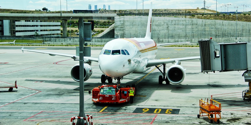 A white plane with blue windows waits on the runway, and at the back are large sheets of glass erected at one of the airports in Sudan.
