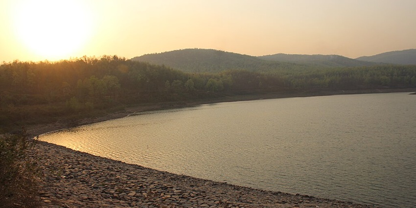 Lake with a small water body surrounded by rocky shorelines and small green hills