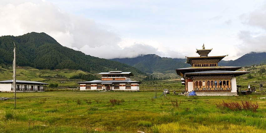 An image of the Khewang Lhakhang, amid green hills and clouds - one of the best places to visit in Phobjikha