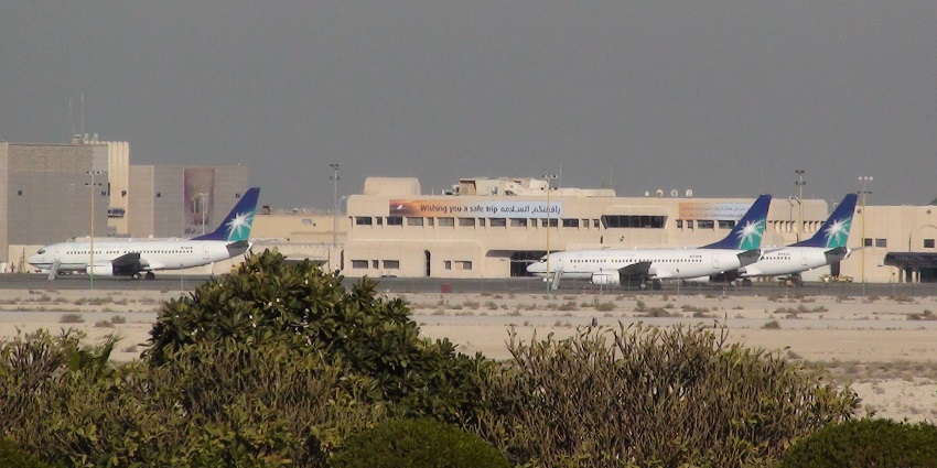 Kind Fahd International Airport with three parked planes and the airport buildings in the back