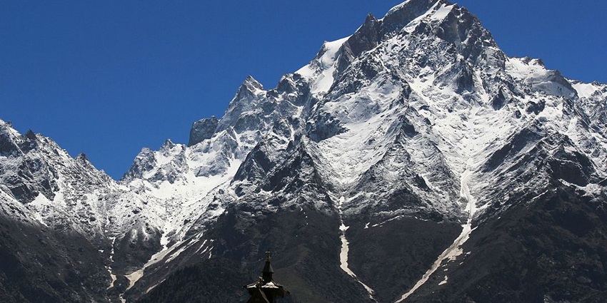 Kinnaur Kailash Peak covered with snow and the top of Kalpa Temple under a blue sky