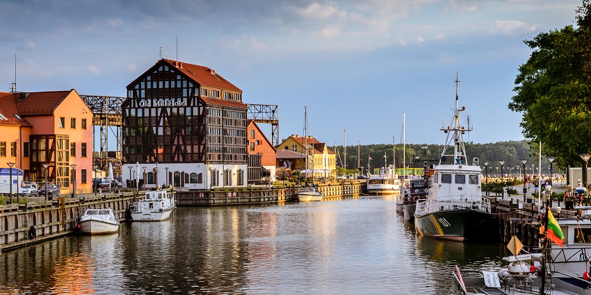 Klaipėda port city skyline reflecting on waters near Galvė Lake during a quiet evening