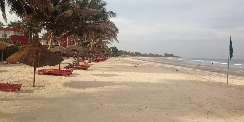 A scenic view of Kotu Beach, The Gambia, with golden sands and red sitting spots.