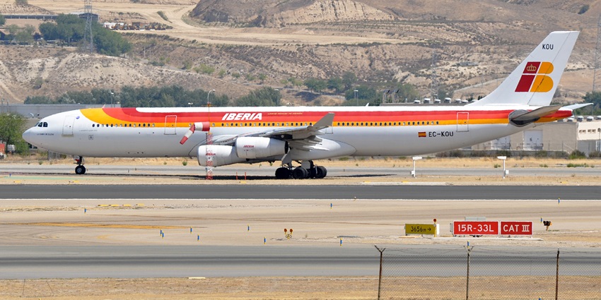 Big commercial aeroplane parked on the runway with orange and red stripes on the aircraft