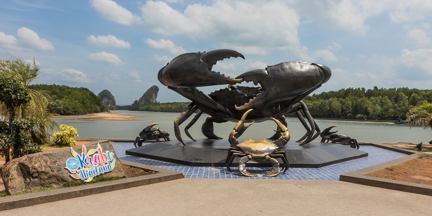 An image of Krabi, Thailand's iconic crab sculpture with greenery and rock formations.