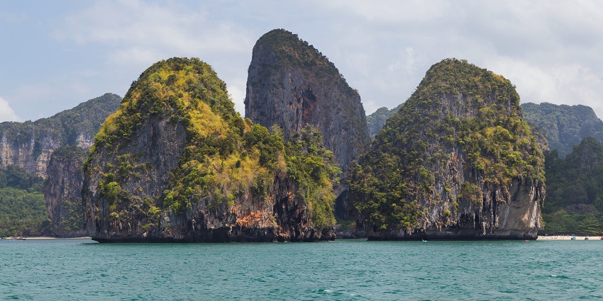 Dramatic limestone karst formations rise against a stunning blue sky, perfect for climbing