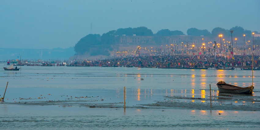 An image of a large procession crossing a bridge with flags, people in robes, and a decorated chariot.
