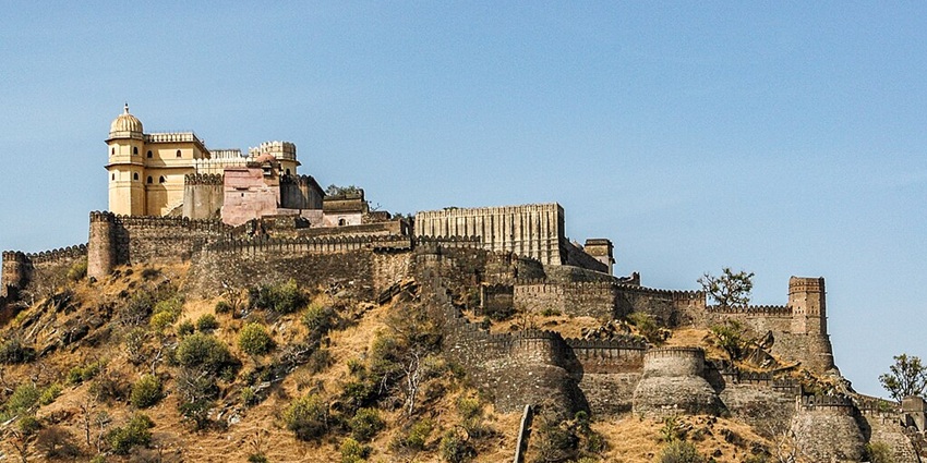 View of the Kumbhalgarh’s mighty wall up on a rugged hill surrounded by lushious fields