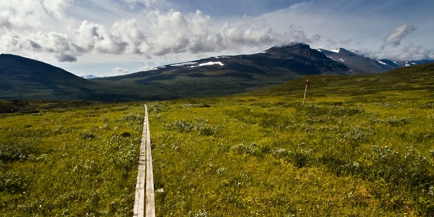 An image of the Kungsleden trail over Teusajaure with rugged terrain and distant peaks
