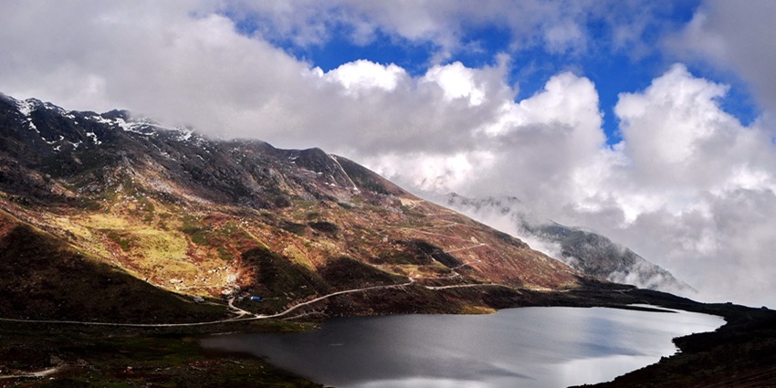 Kupup lake with a small water body, mountains in the back covered in snow and clouds