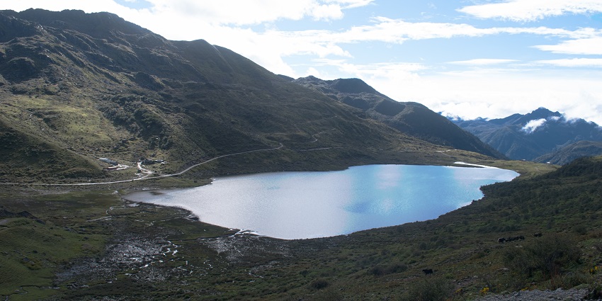 Kupup lake with a small and still water body and a road passing through the mountains.