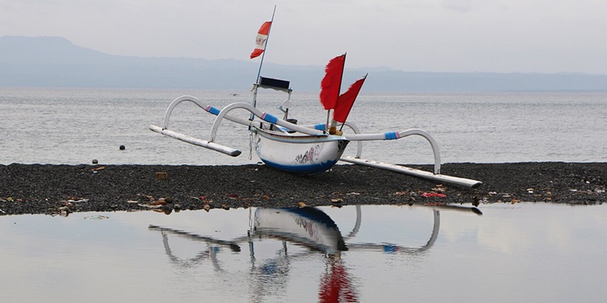A boat seen on the striking black volcanic sands of the Kusamba Beach, located close to the Goa Lawah Temple.
