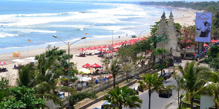 A beautiful sunset view at Kuta Beach with surfers and tourists enjoying the waves.