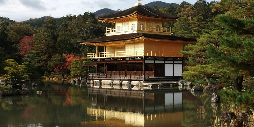 The Golden Pavilion in Kyoto reflects beautifully in a serene pond, surrounded by nature.