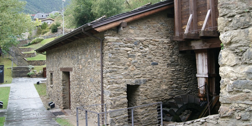 An old stone watermill is standing peacefully while water is flowing through its wheel