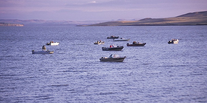 Image of the lake Oahe, with multiple motorboats over it and sand mountains at distance