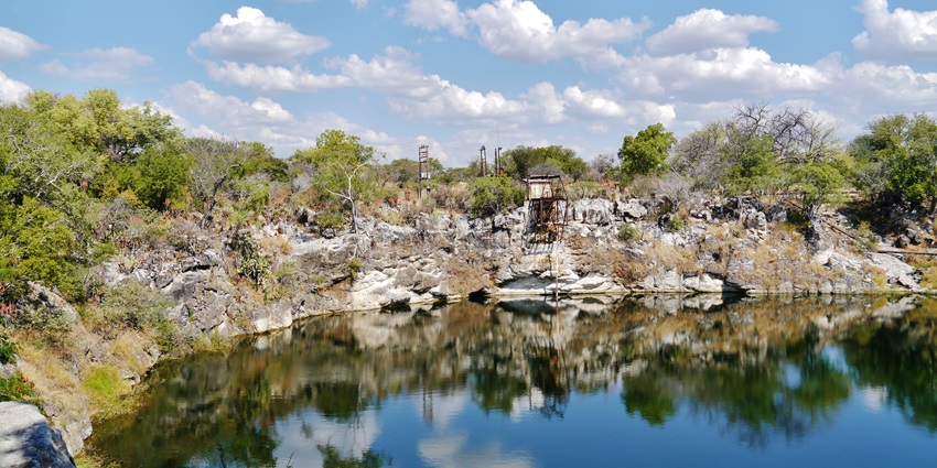 Lake Otjikoto in Namibia with a small water body reflecting the surrounded rocky shores