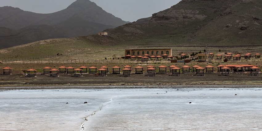 A picture of Lake Urmia’s reddish waters with rugged mountain landscapes surrounding it